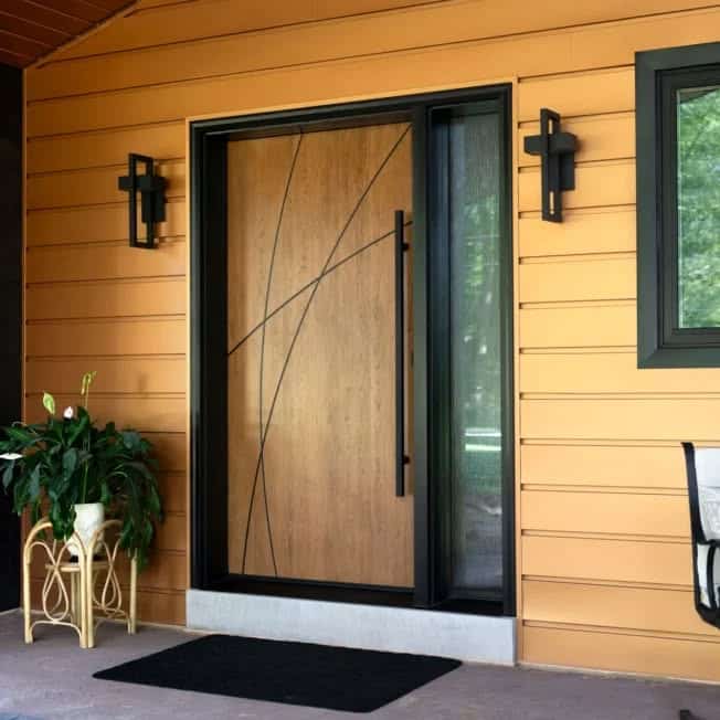 A modern front entrance featuring a natural wood door with black abstract lines, a black frame with a sidelight, warm golden-brown siding, sleek black accents, and a potted plant on a wicker stand for a welcoming touch.