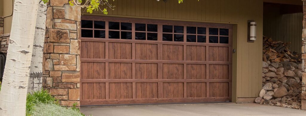 Modern garage door made of steel with a walnut finish. It features a sleek design with horizontal smoked glass windows running across the top section, adding a contemporary and stylish touch. The door is set against a neutral background, emphasizing its elegant and durable appearance.