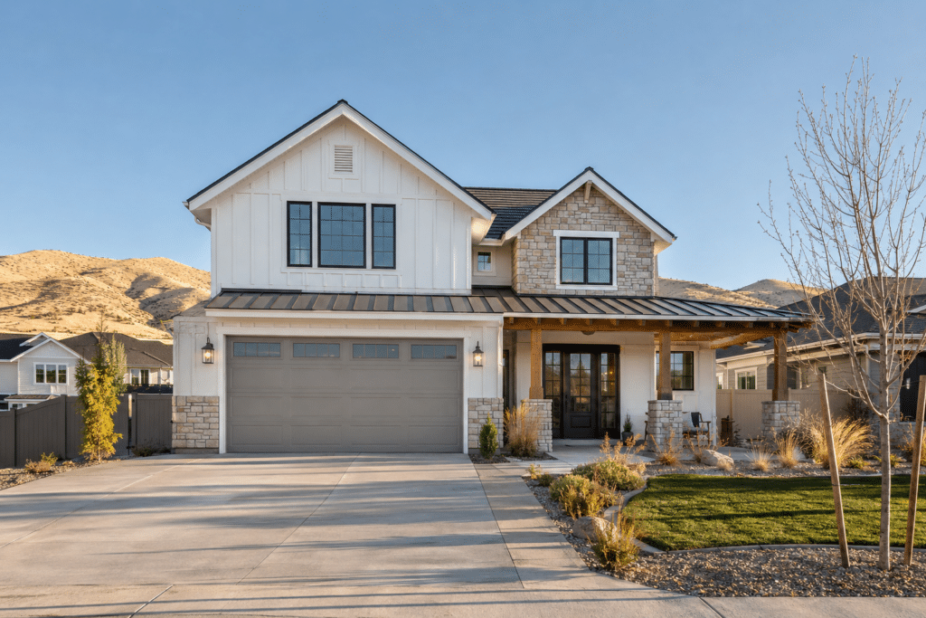 Two-car gray steel garage door on a white modern farmhouse with stone accents in a Treasure Valley subdivision, with the dry Boise foothills behind it