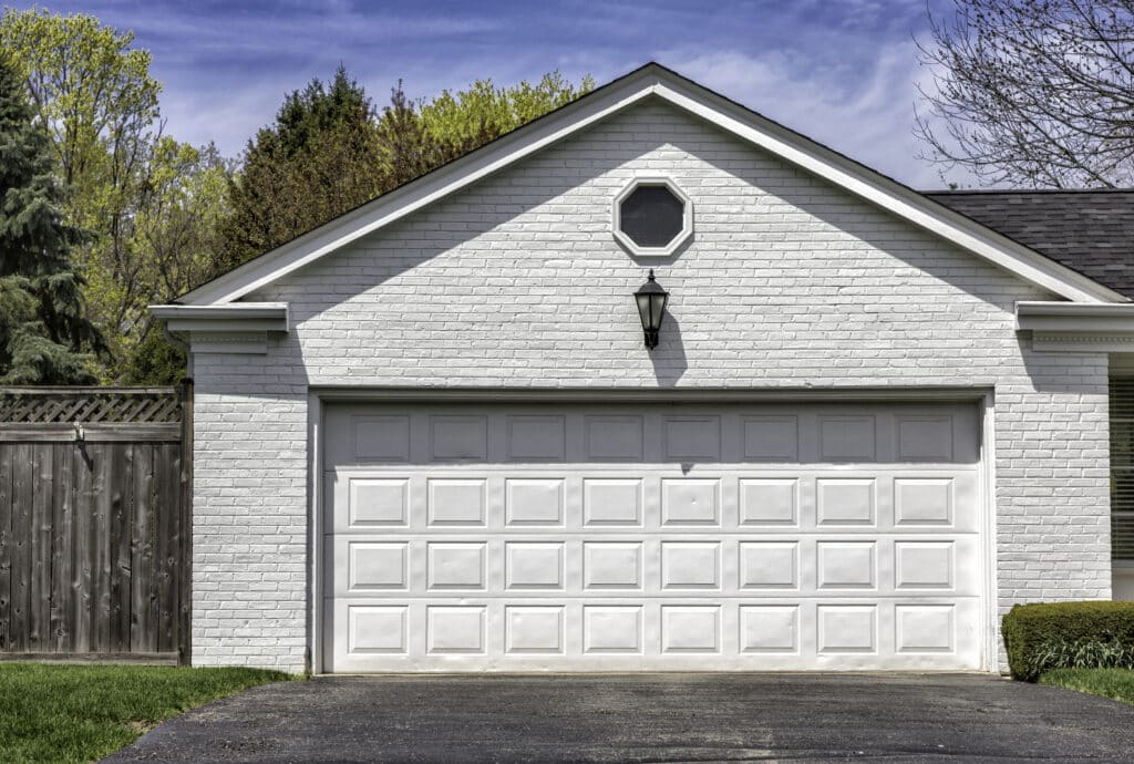 White short-panel double garage door installed on a traditional painted-brick suburban home