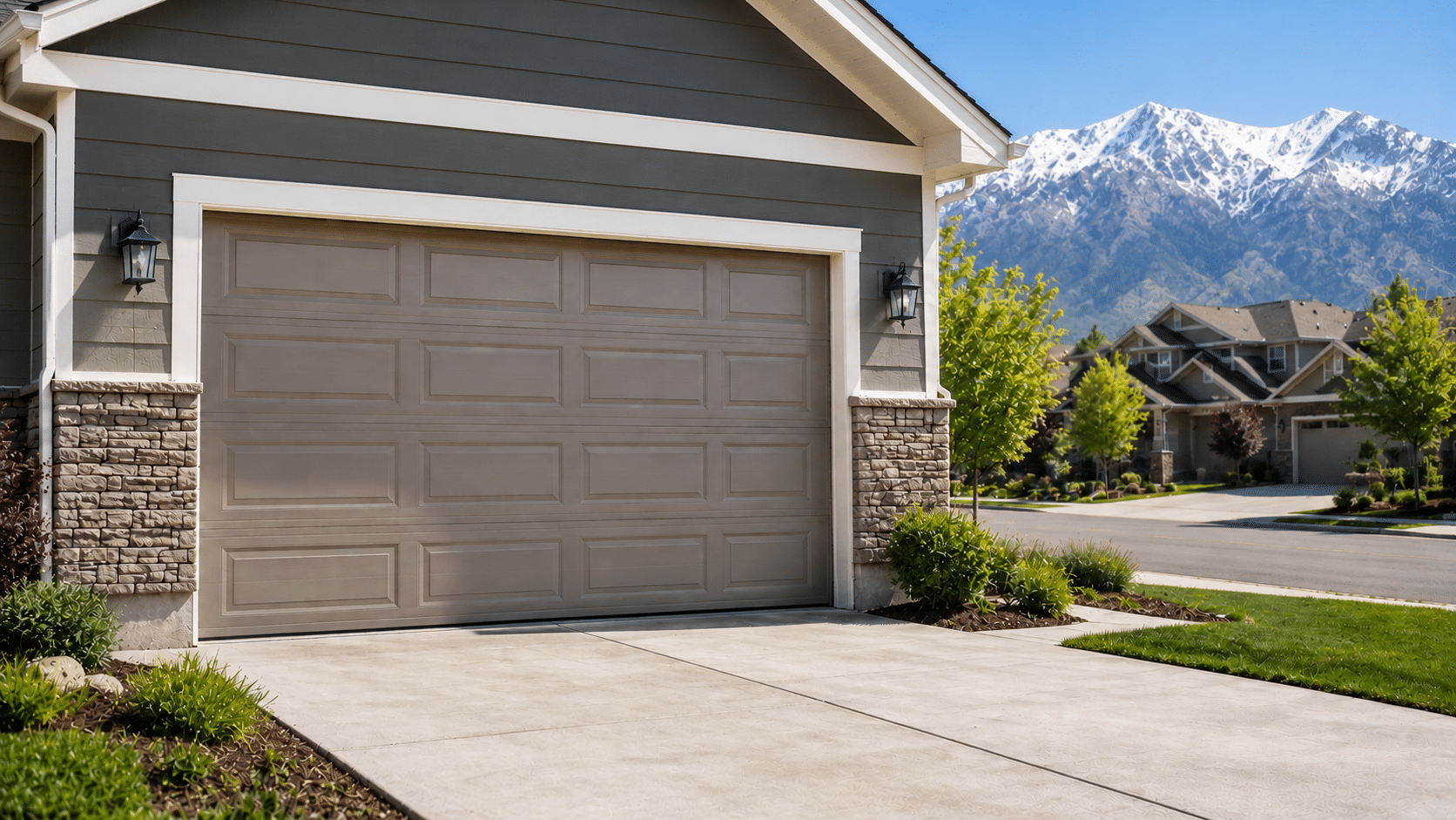 Taupe raised-panel two-car garage door on a Salt Lake City home with the snow-capped Wasatch Range in the background